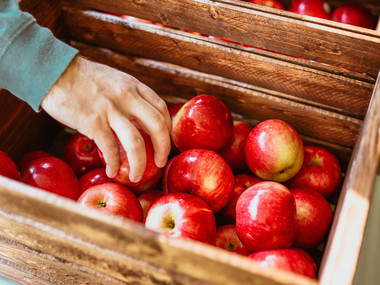 Hand grabbing apples in a wooden box; Photo by Pexels, Josh Hild